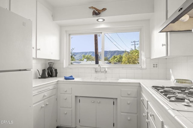406 Santa Ana St, Ojai, CA 93023 - kitchen with freestanding refrigerator, under cabinet range hood, white cabinets, a mountain view, and backsplash