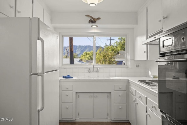 406 Santa Ana St, Ojai, CA 93023 - kitchen with freestanding refrigerator, light countertops, black oven, and white cabinets