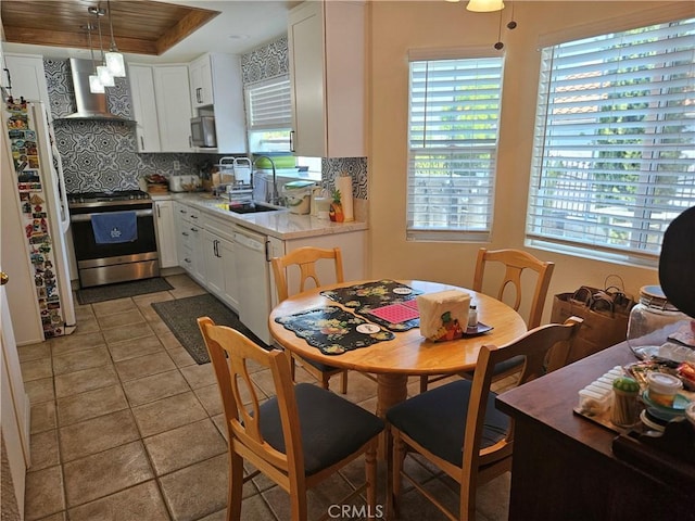 14001 Rabbit Rd, Sylmar, CA 91342 - kitchen with wall chimney range hood, stainless steel appliances, light countertops, backsplash, and white cabinets