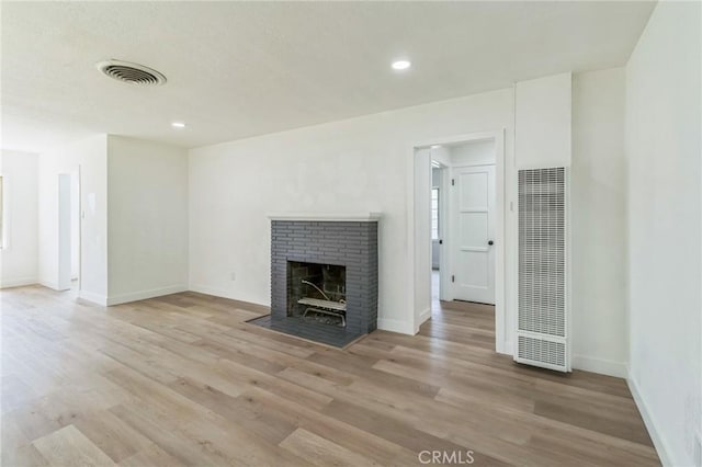 717 La Porte Ave, San Bernardino, CA 92405 - unfurnished living room with a heating unit, light wood-type flooring, a brick fireplace, and recessed lighting