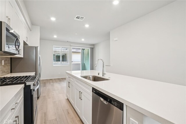 1549 Stratus Dr, Pomona, CA 91768 - kitchen with appliances with stainless steel finishes, white cabinets, recessed lighting, light wood-type flooring, and backsplash