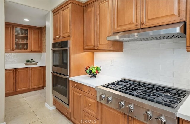 26860 Chaucer Pl, Stevenson Ranch, CA 91381 - kitchen with ventilation hood, appliances with stainless steel finishes, light tile patterned floors, backsplash, and light countertops