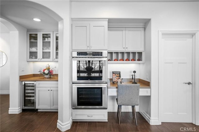 632 Hartwell Ct, Altadena, CA 91001 - kitchen with beverage cooler, double oven, arched walkways, dark wood finished floors, and glass insert cabinets