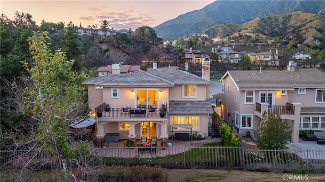 632 Hartwell Ct, Altadena, CA 91001 - back of house at dusk with stucco siding, a balcony, a fenced backyard, a chimney, and a patio area