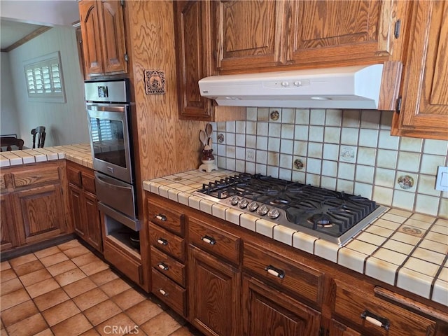 20450 Bassett St, Winnetka, CA 91306 - kitchen featuring appliances with stainless steel finishes, tile counters, range hood, a warming drawer, and tasteful backsplash