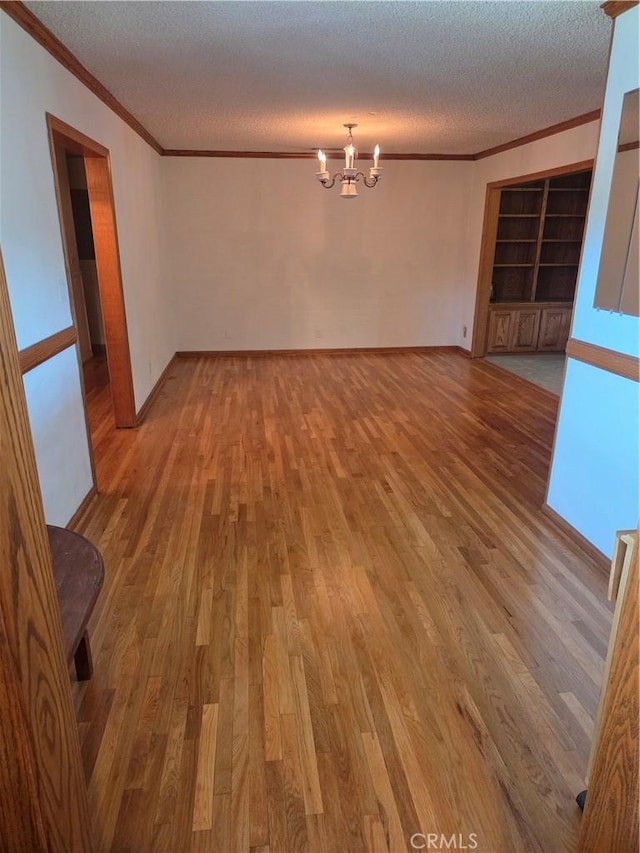 20450 Bassett St, Winnetka, CA 91306 - empty room with crown molding, a chandelier, a textured ceiling, wood finished floors, and built in shelves