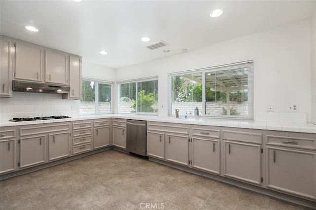 10025 Lubao Ave, Chatsworth, CA 91311 - kitchen with dishwasher, gray cabinets, under cabinet range hood, white gas stovetop, and tasteful backsplash