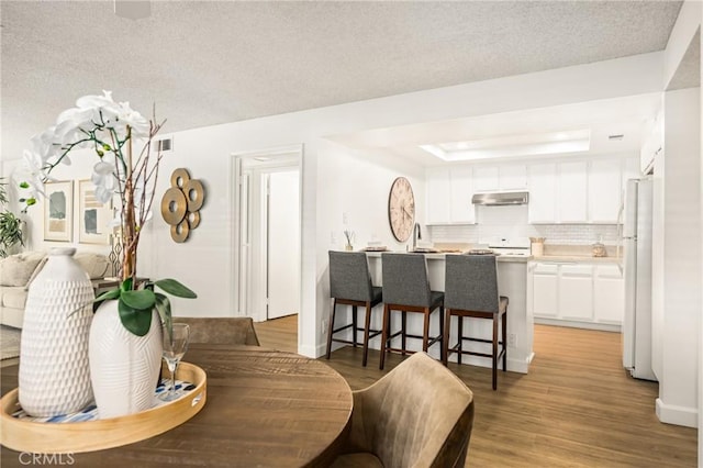 38 Woodleaf, Irvine, CA 92614 - dining room featuring light wood-type flooring, a raised ceiling, and a textured ceiling
