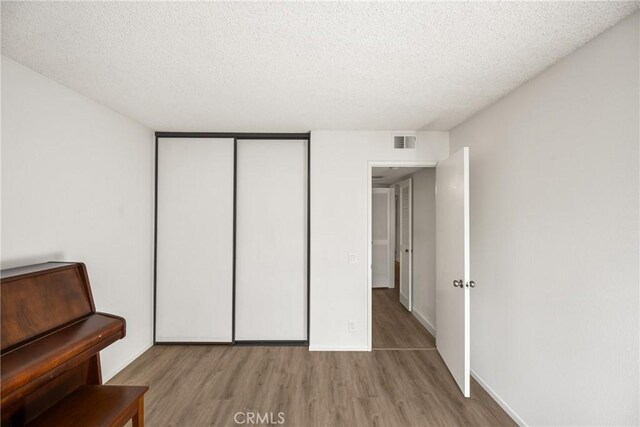 38 Woodleaf, Irvine, CA 92614 - unfurnished bedroom with wood finished floors, a textured ceiling, and a closet