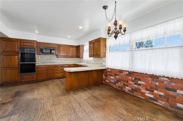 1333 E Tudor St, Covina, CA 91724 - kitchen with black appliances, a peninsula, dark wood-style floors, brown cabinetry, and a chandelier