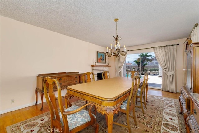 1333 E Tudor St, Covina, CA 91724 - dining room featuring a chandelier, a textured ceiling, a fireplace, and wood finished floors