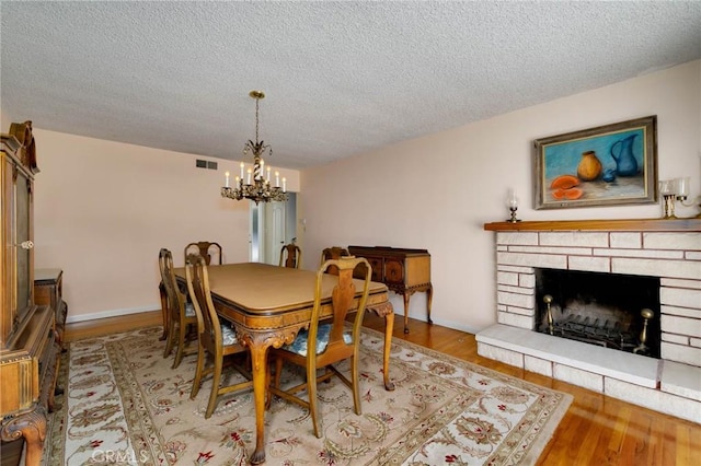 1333 E Tudor St, Covina, CA 91724 - dining area with a chandelier, a textured ceiling, wood finished floors, and a stone fireplace