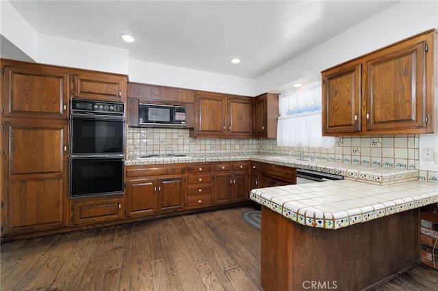 1333 E Tudor St, Covina, CA 91724 - kitchen featuring black appliances, a peninsula, tasteful backsplash, dark wood-style floors, and recessed lighting