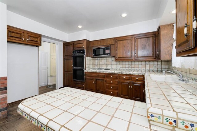 1333 E Tudor St, Covina, CA 91724 - kitchen featuring tile countertops, black appliances, tasteful backsplash, recessed lighting, and a peninsula