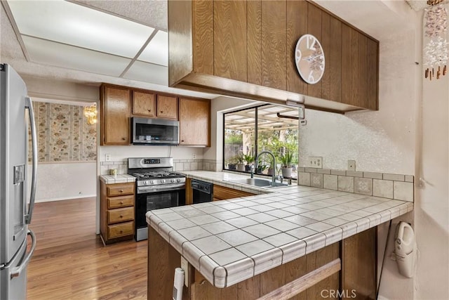 25835 Appian Way, Mission Viejo, CA 92691 - kitchen with appliances with stainless steel finishes, brown cabinets, light wood-type flooring, tile countertops, and a peninsula