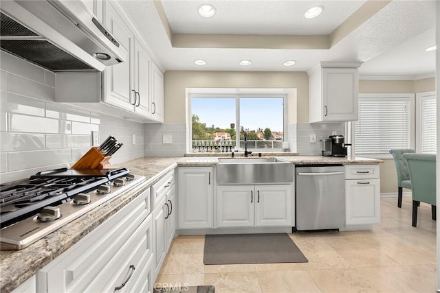 6 Sand Pointe, Laguna Niguel, CA 92677 - kitchen featuring appliances with stainless steel finishes, wall chimney range hood, backsplash, white cabinetry, and crown molding