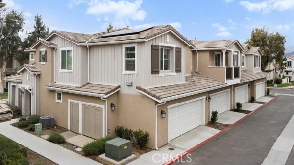 15940 Lasselle St Unit 1, Moreno Valley, CA 92551 - view of property featuring roof mounted solar panels, stucco siding, a tile roof, and an attached garage