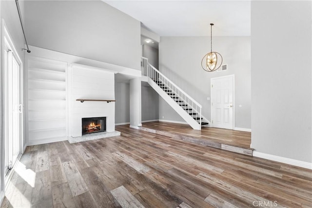 21751 Lanar, Mission Viejo, CA 92692 - unfurnished living room featuring high vaulted ceiling, wood finished floors, a glass covered fireplace, a chandelier, and stairway