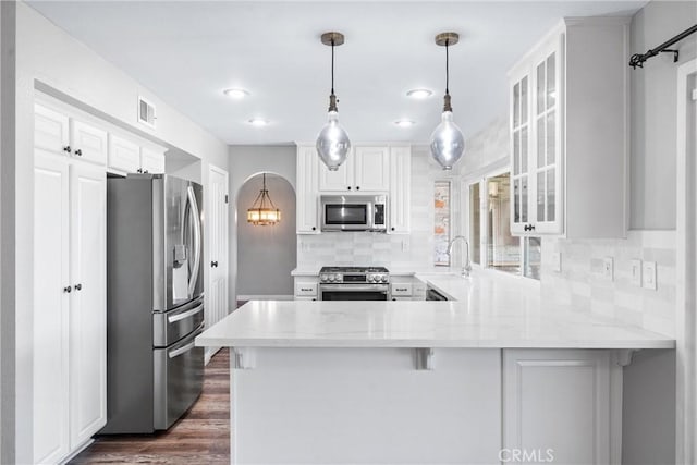 21751 Lanar, Mission Viejo, CA 92692 - kitchen with appliances with stainless steel finishes, a peninsula, backsplash, glass insert cabinets, and light stone countertops