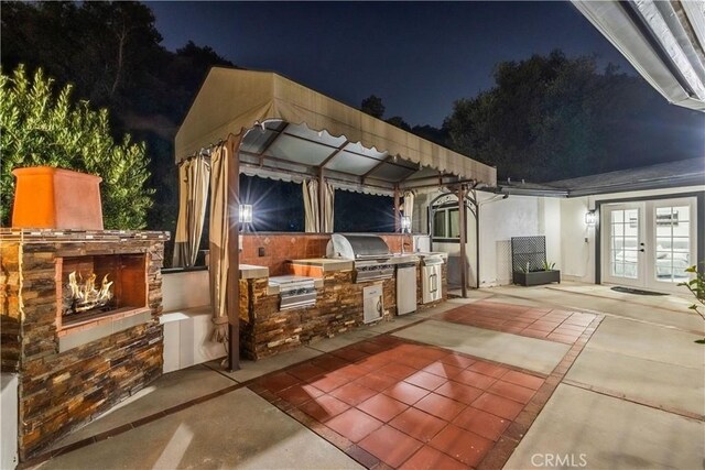 14757 Rockhill Dr, Hacienda Heights, CA 91745 - patio at twilight featuring french doors, exterior kitchen, a lit fireplace, and a patio