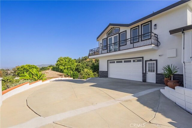 14757 Rockhill Dr, Hacienda Heights, CA 91745 - view of front of home with stucco siding, a balcony, concrete driveway, and stone siding