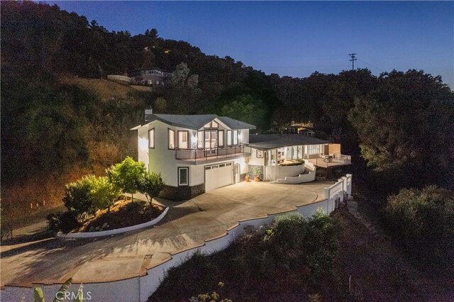 14757 Rockhill Dr, Hacienda Heights, CA 91745 - back of house featuring a garage, stucco siding, driveway, a balcony, and a forest view