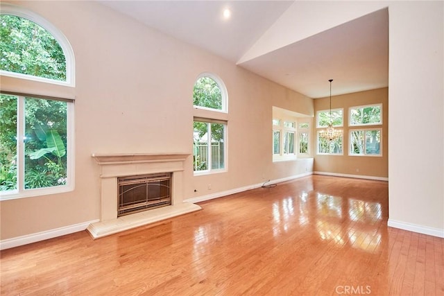 26821 Moore Oaks Rd, Laguna Hills, CA 92653 - unfurnished living room with a chandelier, high vaulted ceiling, wood-type flooring, and a glass covered fireplace