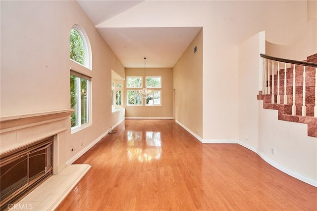 26821 Moore Oaks Rd, Laguna Hills, CA 92653 - unfurnished living room featuring wood finished floors, stairs, a fireplace, and high vaulted ceiling