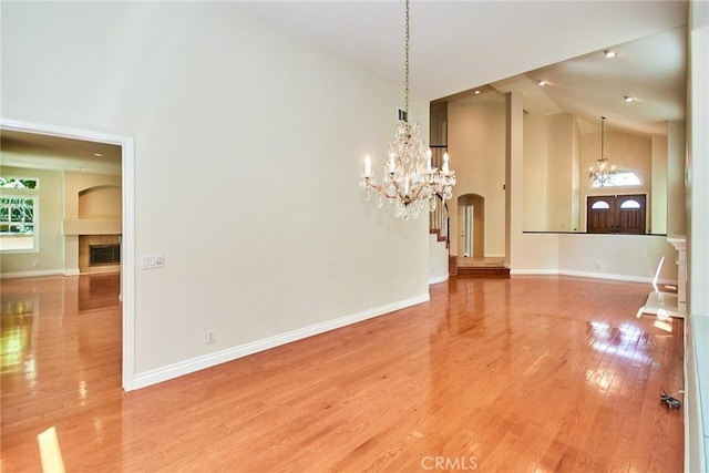 26821 Moore Oaks Rd, Laguna Hills, CA 92653 - unfurnished dining area with high vaulted ceiling, a chandelier, a tiled fireplace, light wood finished floors, and arched walkways