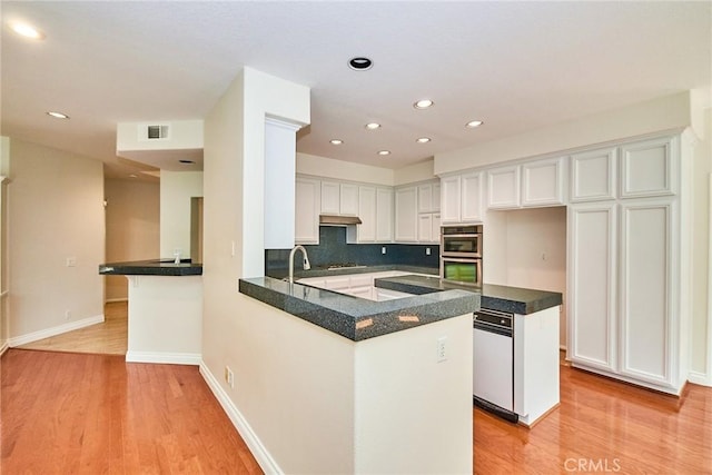 26821 Moore Oaks Rd, Laguna Hills, CA 92653 - kitchen with light wood-style flooring, double oven, a peninsula, white cabinetry, and recessed lighting
