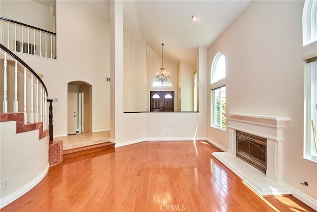 26821 Moore Oaks Rd, Laguna Hills, CA 92653 - unfurnished living room with high vaulted ceiling, wood finished floors, stairway, arched walkways, and a chandelier