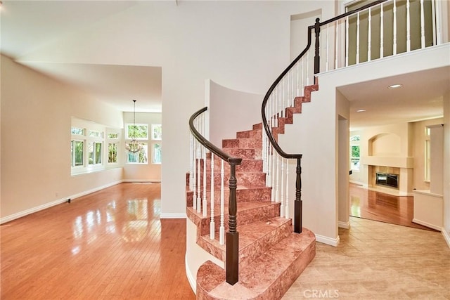 26821 Moore Oaks Rd, Laguna Hills, CA 92653 - stairs with a towering ceiling, a fireplace with flush hearth, wood finished floors, and a chandelier