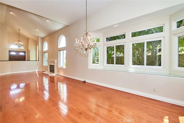 26821 Moore Oaks Rd, Laguna Hills, CA 92653 - unfurnished living room with a chandelier, high vaulted ceiling, wood finished floors, and a glass covered fireplace