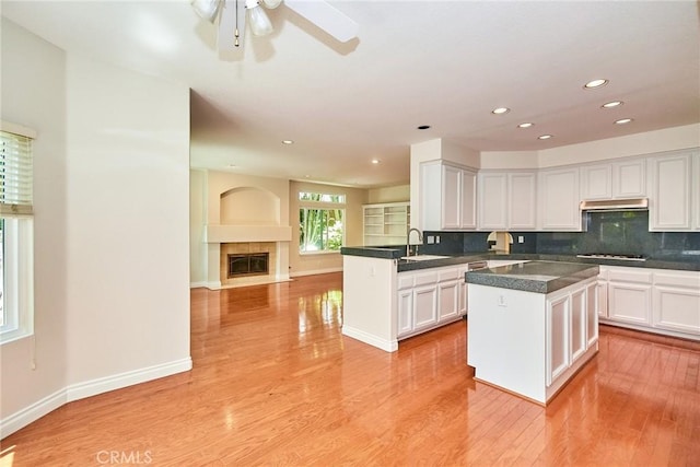 26821 Moore Oaks Rd, Laguna Hills, CA 92653 - kitchen with gas cooktop, white cabinetry, under cabinet range hood, recessed lighting, and light wood-type flooring