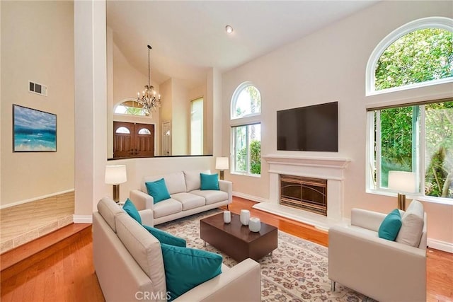 26821 Moore Oaks Rd, Laguna Hills, CA 92653 - living room featuring a chandelier, high vaulted ceiling, wood finished floors, and a glass covered fireplace