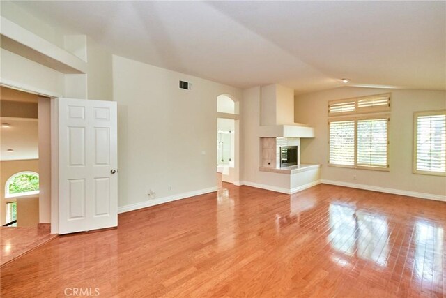 26821 Moore Oaks Rd, Laguna Hills, CA 92653 - unfurnished living room featuring plenty of natural light, vaulted ceiling, light wood-style flooring, and a multi sided fireplace
