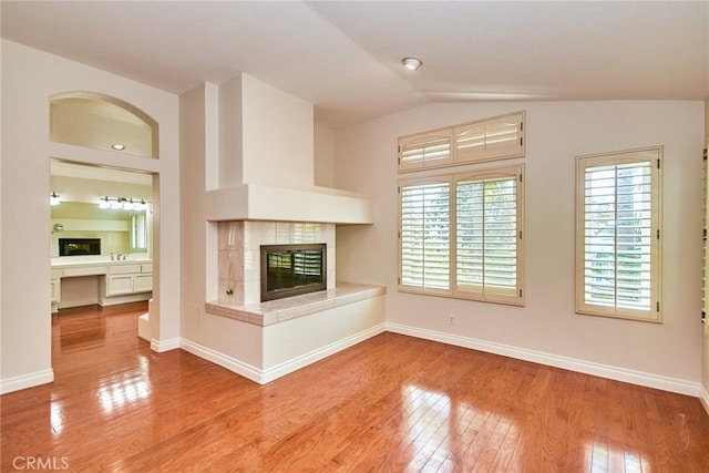 26821 Moore Oaks Rd, Laguna Hills, CA 92653 - unfurnished living room featuring a tiled fireplace, wood finished floors, and lofted ceiling