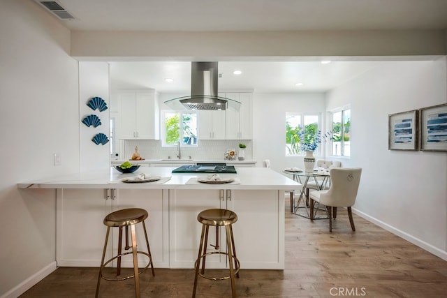 10028 Judy Ct, Riverside, CA 92503 - kitchen with island exhaust hood, white cabinetry, a peninsula, backsplash, and light countertops