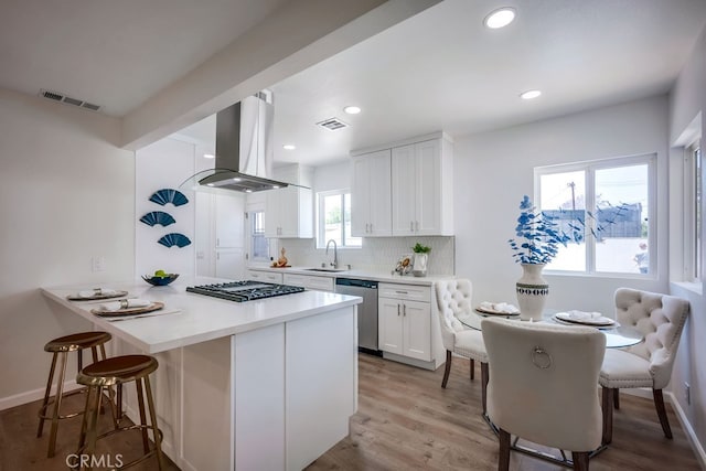 10028 Judy Ct, Riverside, CA 92503 - kitchen featuring dishwasher, island exhaust hood, gas cooktop, a kitchen breakfast bar, and white cabinetry