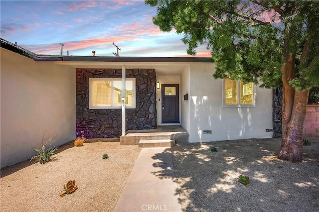 10028 Judy Ct, Riverside, CA 92503 - exterior entry at dusk featuring crawl space, stone siding, and stucco siding