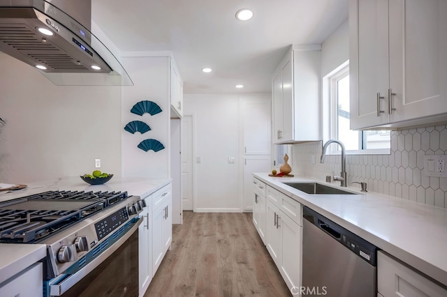 10028 Judy Ct, Riverside, CA 92503 - kitchen featuring appliances with stainless steel finishes, range hood, tasteful backsplash, white cabinetry, and light wood-style flooring