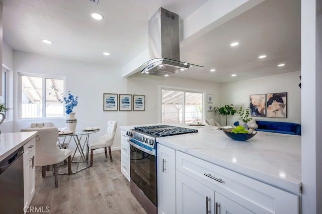 10028 Judy Ct, Riverside, CA 92503 - kitchen featuring appliances with stainless steel finishes, island range hood, white cabinets, light wood-type flooring, and recessed lighting