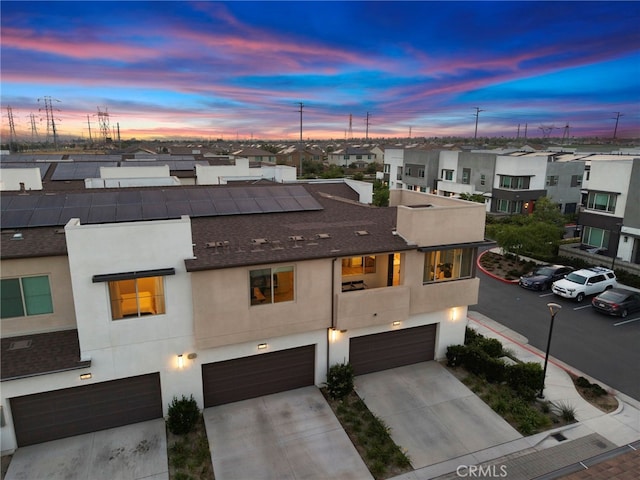 3540 E Peckham Paseo Unit 5, Ontario, CA 91761 - view of front facade featuring an attached garage, a residential view, stucco siding, driveway, and roof mounted solar panels