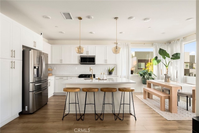 3540 E Peckham Paseo Unit 5, Ontario, CA 91761 - kitchen with stainless steel appliances, wood finished floors, white cabinetry, and light countertops