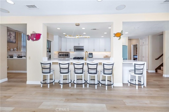 21620 Brisbane Way, Yorba Linda, CA 92887 - kitchen with stainless steel microwave, ventilation hood, a breakfast bar, light countertops, and recessed lighting