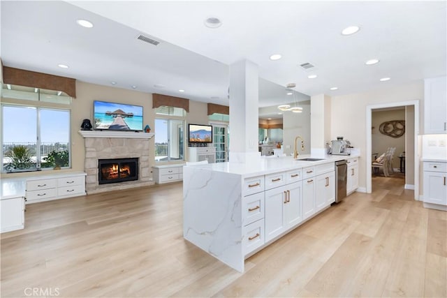 21620 Brisbane Way, Yorba Linda, CA 92887 - kitchen with a stone fireplace, light stone counters, white cabinets, open floor plan, and light wood-type flooring