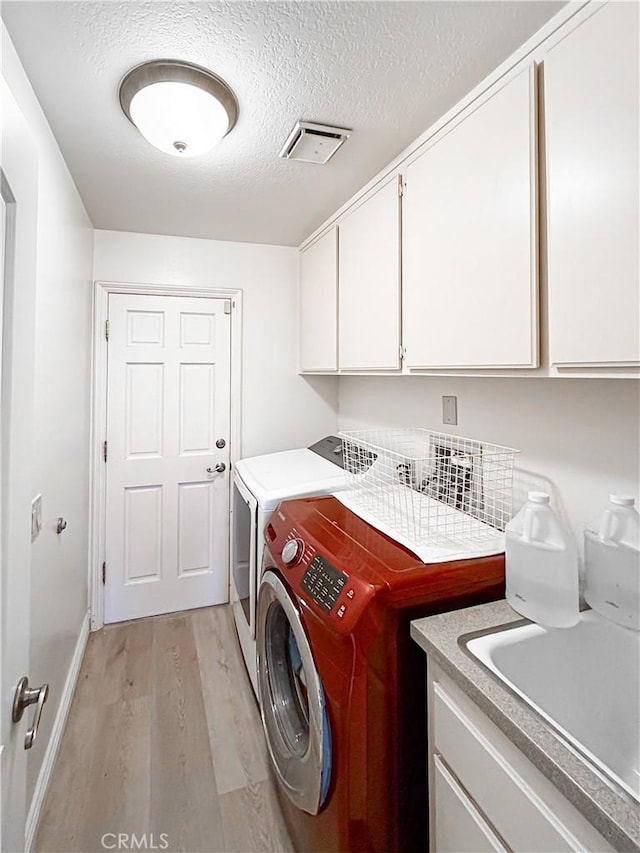21620 Brisbane Way, Yorba Linda, CA 92887 - washroom with cabinet space, washing machine and dryer, light wood finished floors, and a textured ceiling