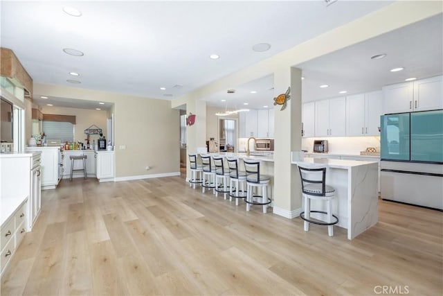 21620 Brisbane Way, Yorba Linda, CA 92887 - kitchen with fridge, a breakfast bar area, white cabinets, light wood-style flooring, and stainless steel microwave