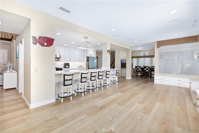 21620 Brisbane Way, Yorba Linda, CA 92887 - kitchen featuring freestanding refrigerator, a kitchen breakfast bar, light wood-style floors, white cabinetry, and light countertops