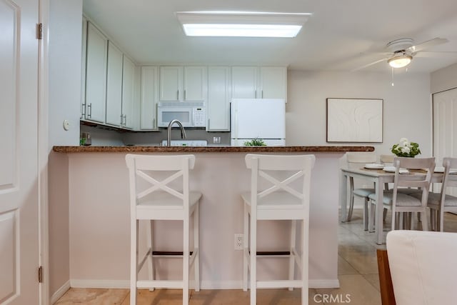 3456 Castle Glen Dr Unit 154, San Diego, CA 92123 - kitchen with white appliances, a breakfast bar, dark stone counters, and light tile patterned flooring